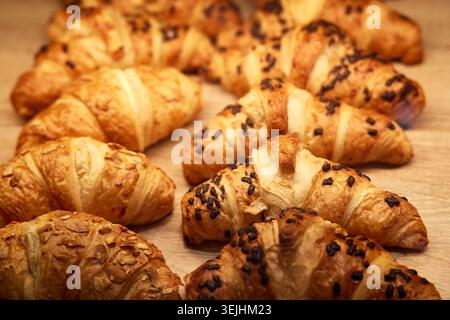 Croissant dorati appena sfornati e pasta al cioccolato su un tavolo di legno. Foto Stock