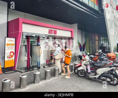 I clienti sono in fila per utilizzare le macchine ATM all'interno di un contenitore rosa brillante, ho chi Minh City, Vietnam, Asia Foto Stock