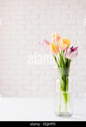 Tulipani color pastello in vaso su sfondo bianco in mattoni Foto Stock