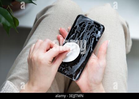Donna che pulisce il telefono cellulare per eliminare germi, batteri Foto Stock