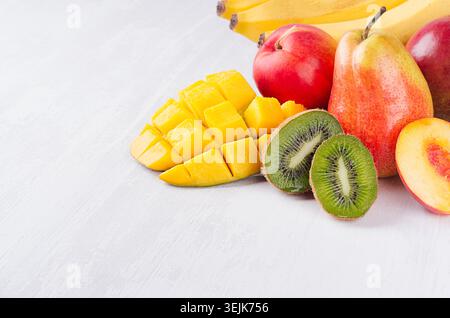 Mix di frutta colorata - frutta intera e succose fette a fette - mango, banana, pera, pesca, kiwi, primo piano di nactarina su bianco morbido con Foto Stock