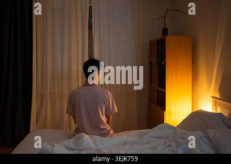 Donna anziana e premurosa seduta a letto a tarda notte, riflettendo sui problemi e le preoccupazioni della vita. Foto Stock