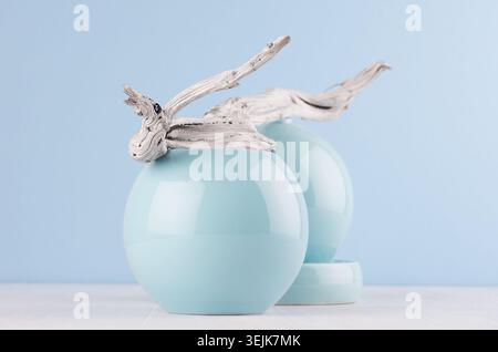 Design di moda giovanile nell'arredamento della casa - vaso liscio blu pastello e pezzo di legno grigio scassinato su tavola di legno bianca. Foto Stock
