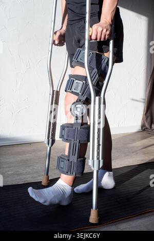 Donna che indossa un sostegno per il ginocchio o un ginocchio dopo un intervento chirurgico alla gamba Foto Stock