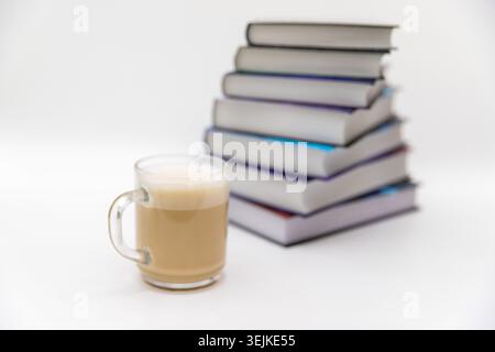 Una pila di libri e tazze da caffè su sfondo bianco, lettura e concetto educativo Foto Stock