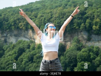 Bella giovane donna con chiuse afro che cammina in montagna Foto Stock