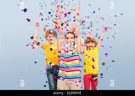 Famiglia felice mamma e due figli fratello e sorella con coriandoli su colorato Foto Stock