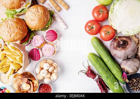 Concetto di cibo sano e malsano. Frutta e verdura a confronto con dolci e fast food Foto Stock