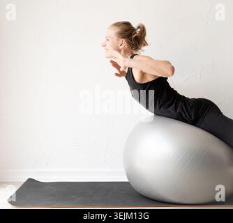 Giovane donna sportiva che si allena sulla palla fitness Foto Stock