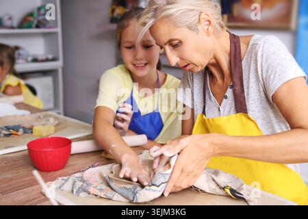 Madre e figlia di bambino modellati in argilla a lezione di ceramica Foto Stock