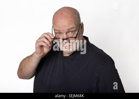 Uomo anziano sicuro che guarda gli occhiali alla fotocamera isolata su sfondo bianco Foto Stock
