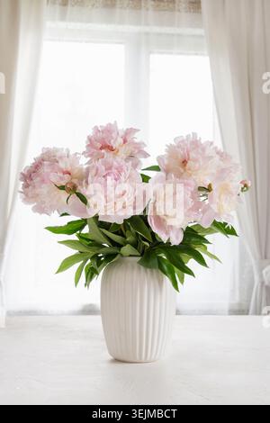 Grande bouquet di peonie rosa in vaso bianco alla finestra Foto Stock