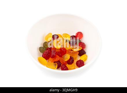 Ammasso di caramelle gommose di frutta in una ciotola isolata, pillole vegane di marmellata da masticare, mucche di gelatina colorate su sfondo bianco Foto Stock
