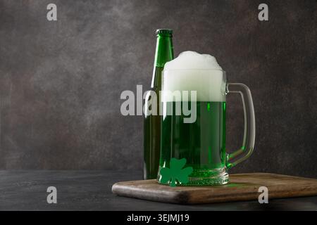 Birra verde giorno di Patrick in pinta su sfondo scuro. Shamrock simbolo di fortuna. Foto Stock