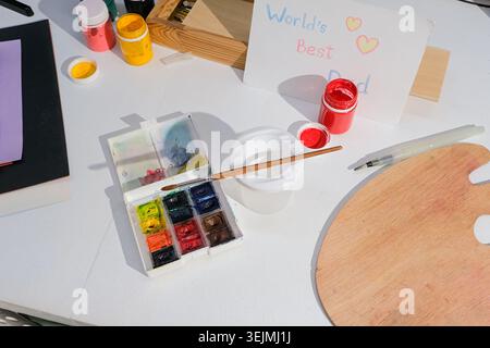 Vernici ad acquerello, pennelli e altre forniture scolastiche sulla scrivania Foto Stock