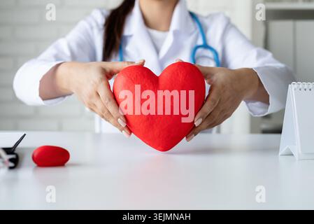 Medico o scienziato donna che tiene in mano un grande cuore rosso Foto Stock
