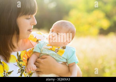 Felice madre amorevole e il suo bambino appena nato in estate sulla natura Foto Stock