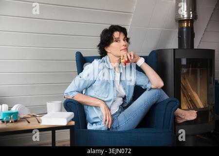 Stile di vita sano. rilassatevi a casa. ritratti una donna di mezza età sorridente che pensa e guarda la fotocamera a casa Foto Stock