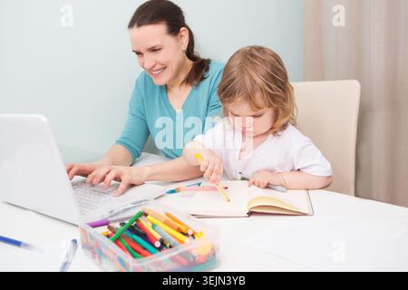 Una madre che lavora a casa e che ha un figlio. Foto Stock