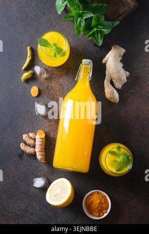 Bevanda a base di erbe indonesiana Jamu con ingredienti naturali curcuma, zenzero su sfondo marrone. Verticale. Vista dall'alto. Foto Stock