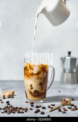 Caffè a latte freddo in bicchiere da tazza con il latte versato Foto Stock