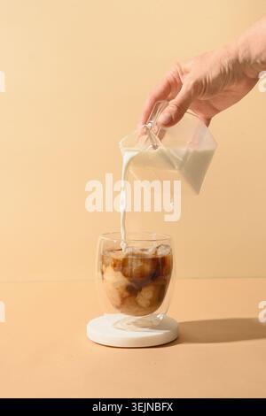 Caffè a latte freddo in bicchiere da tazza con il latte versato Foto Stock