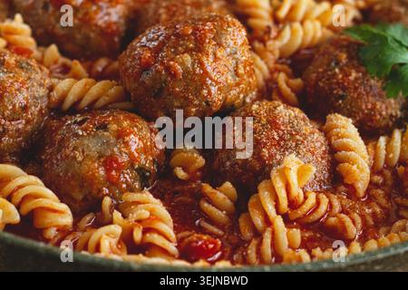 Polpette di carne macinata, in salsa di pomodoro, con pasta fusilli, in padella di ghisa, fatte in casa, senza persone, Foto Stock