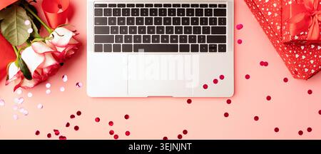 Vista dall'alto dello spazio di lavoro diurno di San Valentino con tastiera per computer portatile, fiori e confezioni regalo Foto Stock