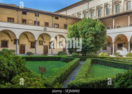 Basilica di San Lorenzo a Firenze, vista sul chiostro. Architettura rinascimentale con luce soffusa su archi in pietra Foto Stock