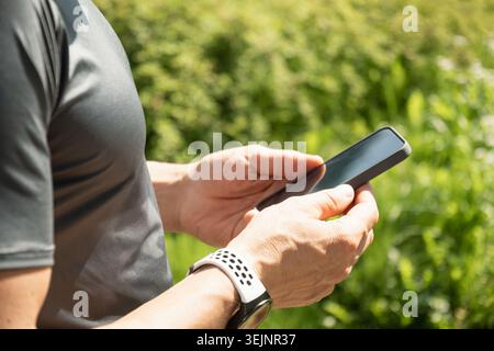 Uomo con le mani che tiene lo smartphone in esterni Foto Stock