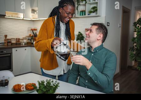 Felice coppia interrazziale che gusta la colazione insieme in cucina Foto Stock