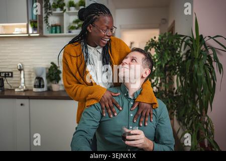 Coppia interrazziale che condivide un tenero momento amorevole in cucina Foto Stock