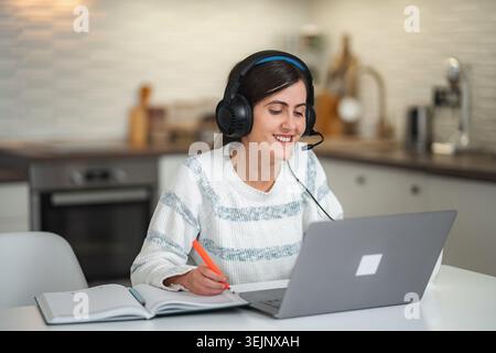 Giovane donna sorridente che lavora da casa utilizzando un notebook Foto Stock