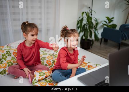 Ragazze che si divertono a videochiamare con un notebook a casa Foto Stock