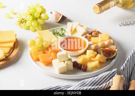Piatto di formaggi con uva, noci, fichi su sfondo bianco. Foto Stock