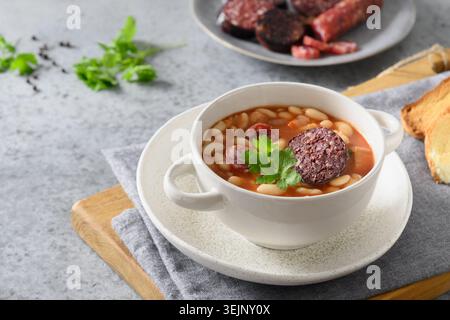 Stufato di fabada spagnola con salsiccia di sangue su un tavolo grigio. Foto Stock