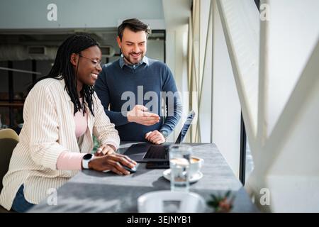 Diversi colleghi aziendali che collaborano con un notebook in un ufficio moderno Foto Stock