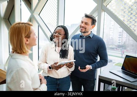 Colleghi diversi che collaborano in ufficio con un tablet digitale Foto Stock