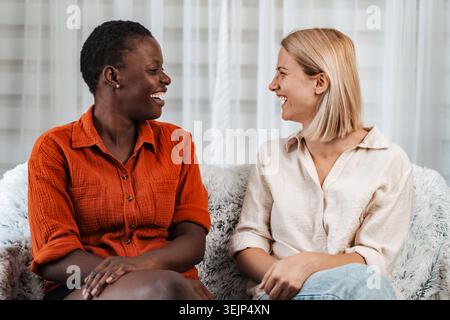 Due giovani donne che sorridono e parlano su un divano Foto Stock
