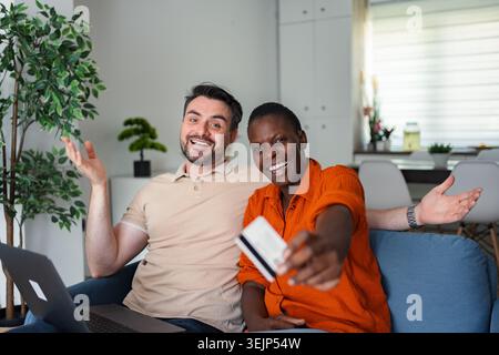 Coppia entusiasta che fa acquisti online con carta di credito e laptop a casa Foto Stock