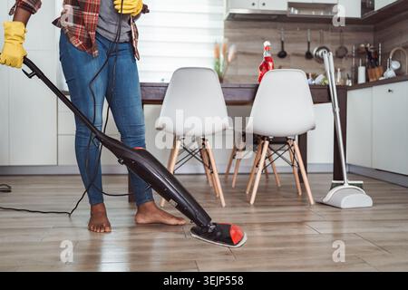 Donna che pulisce il pavimento della cucina con uno straccio a vapore Foto Stock