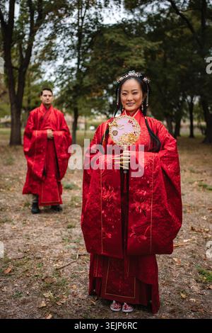 Coppie di nozze multiculturali che festeggiano con abiti tradizionali cinesi Foto Stock