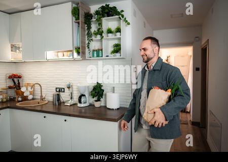 Uomo che torna a casa con un sacco di carta in cucina Foto Stock