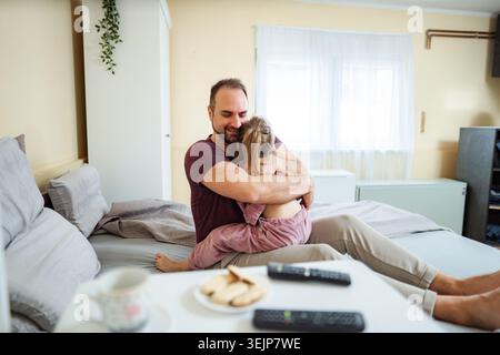 Padre e figlia che si abbracciano in camera da letto godendosi la mattinata insieme Foto Stock