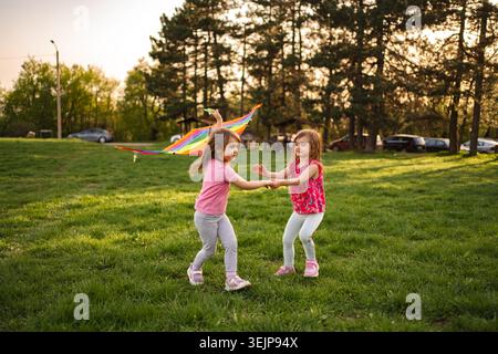 Momenti di gioia condivisi da due ragazze che giocano con un aquilone colorato Foto Stock