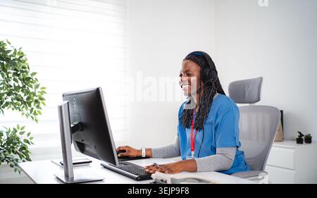 Donna afroamericana sorridente mentre lavora al computer in ufficio Foto Stock