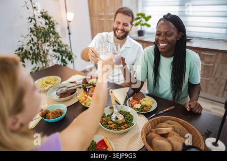 Amici che si godono un pasto in una cucina accogliente Foto Stock