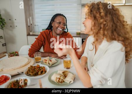 Amici diversi che ridono e pranzano insieme godendo di una conversazione Foto Stock