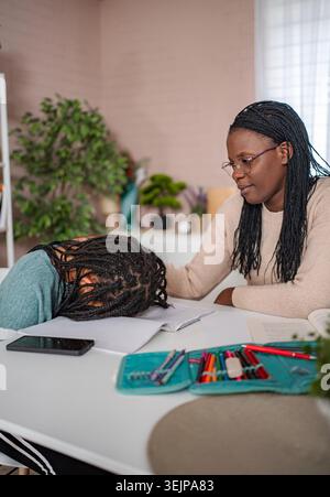Madre conforta il bambino stanco che ha difficoltà con il lavoro scolastico Foto Stock
