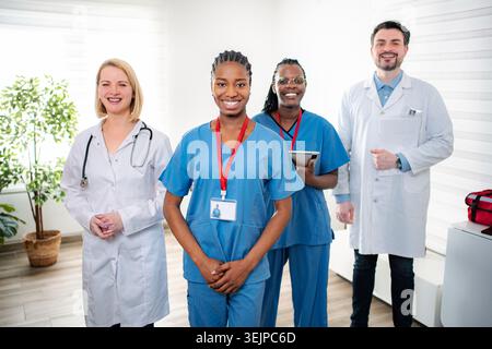 Team medico diversificato in piedi insieme sorridendo in clinica Foto Stock